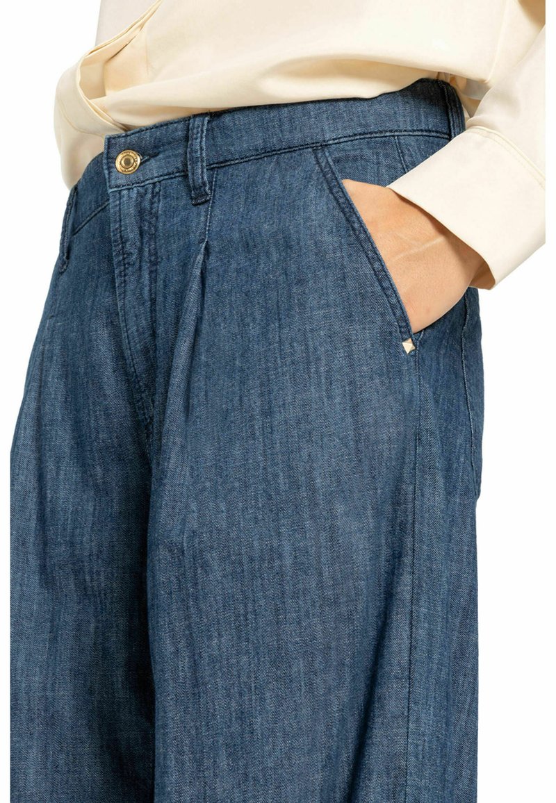 Denim broek in een donkerblauwe kleur, met een knoopsluiting, zijzakken en een relaxte pasvorm met een subtiele textuur. Verfraaid met kleine hardware details.