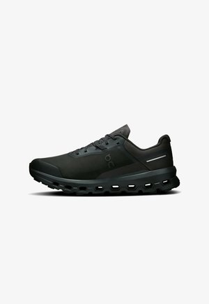 Chaussures de sport noires avec une tige en tissu lisse, des détails en mesh à motifs, un design à lacets et une semelle épaisse et rembourrée avec des sections découpées.