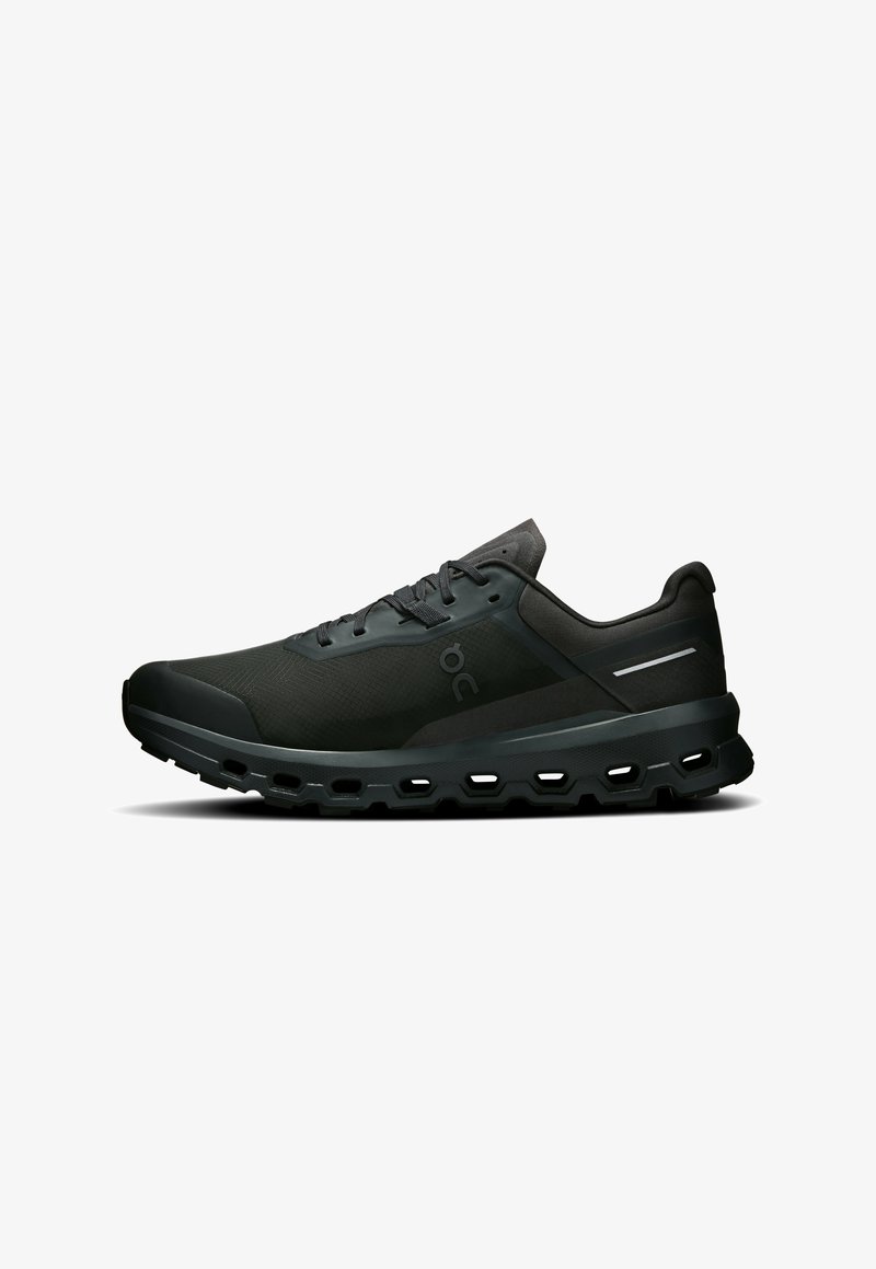 Chaussures de sport noires avec une tige en tissu lisse, des détails en mesh à motifs, un design à lacets et une semelle épaisse et rembourrée avec des sections découpées.