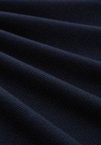 Tissu bleu marine foncé avec un motif tricoté texturé en côtes, disposé en douces plis horizontaux.