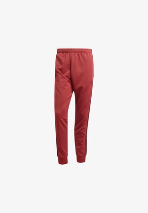 Pantalones deportivos rojos con una cinturilla elástica, puños cónicos en los tobillos y franjas laterales negras. Presenta un pequeño logo negro en el muslo.