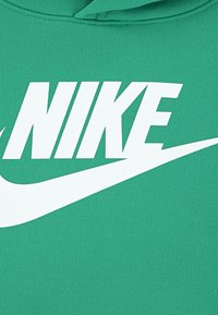 Un sweat à capuche vert arborant un grand logo "NIKE" blanc sur la poitrine avec un graphique de swoosh. Le matériau est texturé et côtelé.