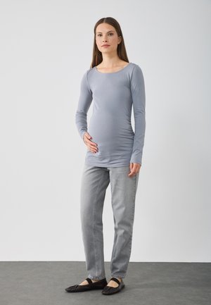 Grijze lange mouwen top met een ronde hals, aangesloten stijl en ruches aan de zijkanten, gecombineerd met lichtgrijze rechte jeans en zwarte ballerina's.