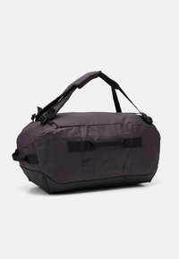 Borsa a duffel viola realizzata in tessuto durevole con dettagli neri, dotata di una maniglia robusta e cinture regolabili, logo stampato sul lato.