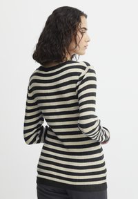 Stribet ribbet sweater i sort og creme med lange ærmer og rund halsudskæring. Blød tekstur med en tætsiddende silhuet.