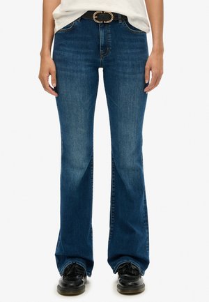 Jeans de mezclilla azul acampanados con un lavado medio, ajuste de cintura alta y un ligero desvanecido. Acabados con costuras tonales y pasadores para cinturón.