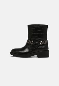 Czarny botek skórzany z tłoczeniem imitującym skórę krokodyla, z masywnym obcasem i ozdobnym paskiem z nitami. Boczny zamek błyskawiczny ułatwiający zakładanie. Teksturowana powierzchnia.