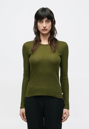 Μακρυμάνικο τοπ σε ελιά πράσινο με ριγέ υφή, στρογγυλή λαιμόκοψη και στενή γραμμή, με διακριτική υφή και ελαφριά φούντα στο τελείωμα.