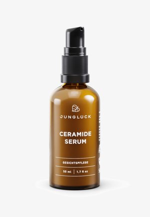 Amber glass bottle with a black pump nozzle. White text labels read "JUNGLÜCK" and "CERAMIDE SERUM," along with volume details.