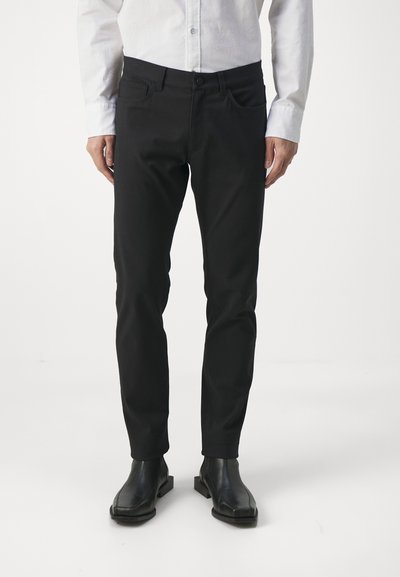 Pantalon noir à coupe ajustée, fabriqué en tissu lisse. Comprend deux poches avant, des passants de ceinture et une fermeture à bouton.