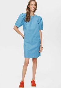 Modra črtasta obleka s kratkimi napihnjenimi rokavi, do kolen, izdelana iz gladkega blaga. V kompletu z rdečimi supergami in kovinskimi dodatki.