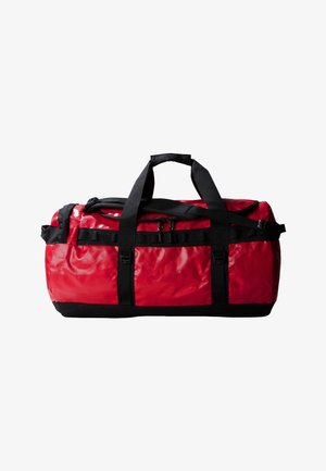 Red duffel bag with a shiny texture, black straps, and a zippered top. Features side buckles and a reinforced bottom for durability.