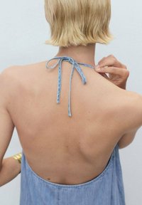 Denimmekko avoimella selällä, jossa on solmimisviimeistely vaaleansinisestä kankaasta. Sujuva rakenne, rento muotoilu ja minimalistinen tyyli.