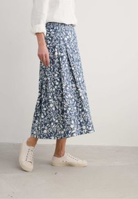 Sininen ja valkoinen kukkakuosiseksi, laskostettu midi-hame. Yhdistetty vaaleanbeigeihin lenkkareihin. Yksinkertainen, rento muotoilu ja kohtuullinen pituus.