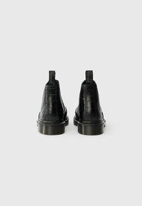 Μαύρες δερμάτινες μπότες αστραγάλου με σχέδιο κροκοδείλου, υφή και λαστιχένιες σόλες. Διαθέτουν γλωττίδες για εύκολη φόρεση.