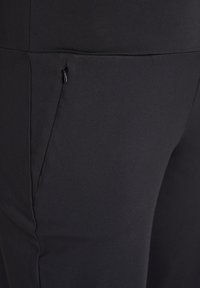 Schwarze Leggings mit einer glatten, dehnbaren Textur, ausgestattet mit einer Seitentasche und einem flachen Taillenbund-Design.