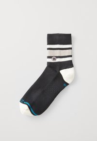Calzino alla caviglia nero con strisce bianche, grigie e nere sulla parte superiore. Presenta un design testurizzato sulla parte del piede e una punta di colore chiaro.