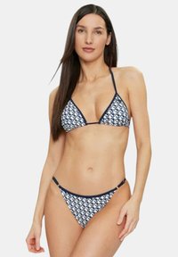 Bikini blu navy con top a triangolo e slip a vita bassa coordinati, decorati con un motivo bianco e spalline sottili.