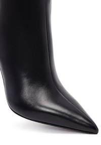Bottines noires en cuir à talons hauts avec une pointe effilée, texture lisse et design épuré. Disposent d'un talon fin et de détails de couture subtils.