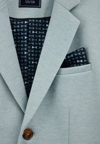 Svetlo modra teksturirana blazer jakna z enim rjavim gumbom, z geometrijskim vzorcem temne podloge in žepno rutico.