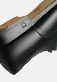 Schwarze Lederschuhe mit einer abgerundeten Zehenpartie, glatter Oberfläche und hellbrauner Innensohle. Verfügt über dezente Nähte und eine strapazierfähige Sohle.