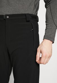 Black pants with a sleek design, made of soft fabric. Features a side zip pocket, button closure, and adjustable waistband accents.