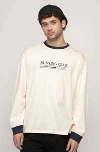 Kremfarget langermet t-skjorte med marineblå krage og mansjetter, med grafikk av "RUNNING CLUB" i mørkeblått. Laget av bomull, med avslappet passform.