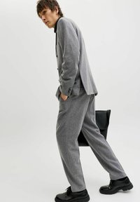 Grå skreddersydd dress laget av teksturert stoff, med en enkeltspent jakke, bukser med avslappet passform og svarte lærsko.