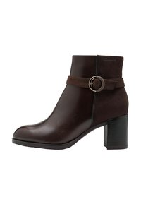 Bottine marron avec un bout arrondi, faite en cuir et en daim, présentant une bande texturée et un accent de boucle circulaire en métal. Talon bloc.