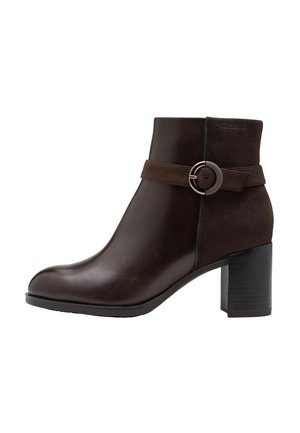 Bottine marron avec un bout arrondi, faite en cuir et en daim, présentant une bande texturée et un accent de boucle circulaire en métal. Talon bloc.