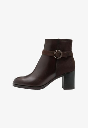 Bruine enkelboot met een ronde neus, gemaakt van leer en suede, met een gestructureerde band en een metalen ronde gespaccent. Blokhak.