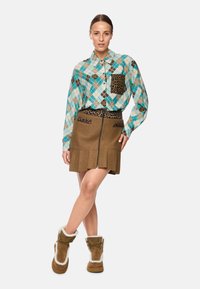 Multicolored plaid shirt with leopard print accents, paired with a brown skirt featuring a zipper and pleated design. Brown fur-lined boots.