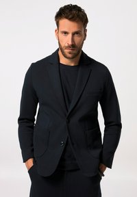 Blazer navy realizzato in tessuto liscio con una vestibilità su misura. Presenta un colletto a scaldamuscolo, chiusura con bottone e due tasche frontali.
