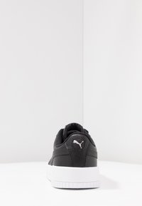 Black textured leather sneaker with white rubber sole, featuring a Puma logo on the back. Slight padding at the collar for comfort.