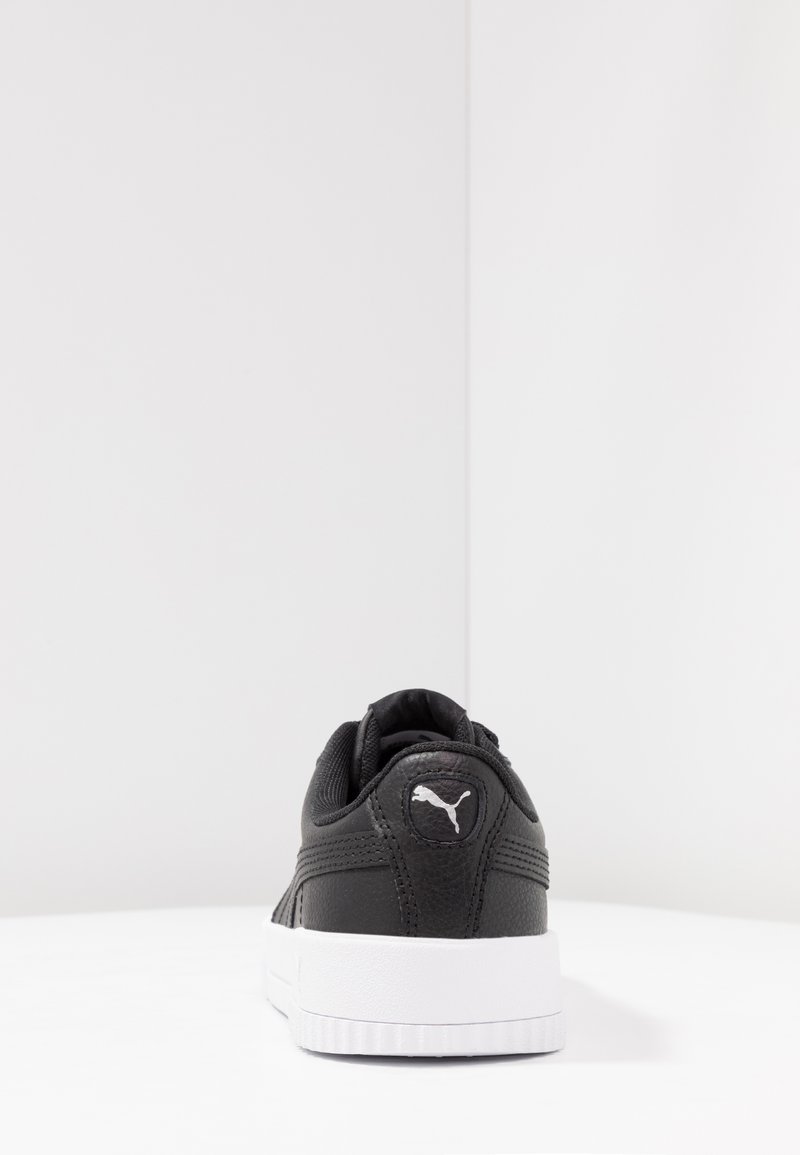 Baskets noires en cuir texturé avec semelle en caoutchouc blanc, présentant un logo Puma à l'arrière. Légère rembourrage au niveau du col pour le confort.