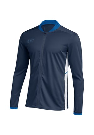 Dunkelblaue Sportjacke mit durchgehendem Reißverschluss, langen Ärmeln, hellblauem Kragen und Bündchen, weißen Seitenpartien und kleinem Swoosh-Logo auf der Brust.