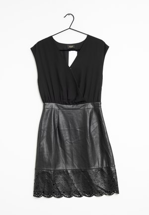 Abito nero con top a scollo a V e gonna a strati in pelle perforata. Caratterizzato da una schiena a occhiale e un orlo scallopato tagliato al laser.