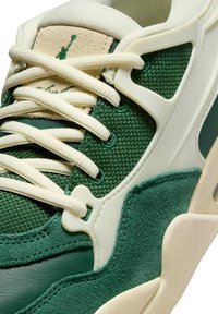 Sneaker verde con tomaia in mesh e suede, lacci color crema e dettagli in plastica. Presenta un design testurizzato e una linguetta imbottita.