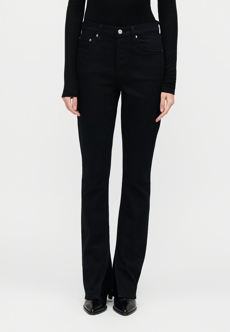 Μαύρα τζιν με φαρδιά μπότα και ψηλή μέση, κατασκε υασμένα από τζιν ύφασμα. Διαθέτουν μπροστινές τσέπες, ασημένιες λεπτομέρειες και καθαρές ραφές χωρίς διακοσμητικά στοιχεία.