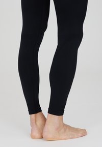 Sorte leggings lavet af et strækbart materiale, med en tætsiddende design, ribbede manchetter og en glat tekstur, der strækker sig til bare fødder.