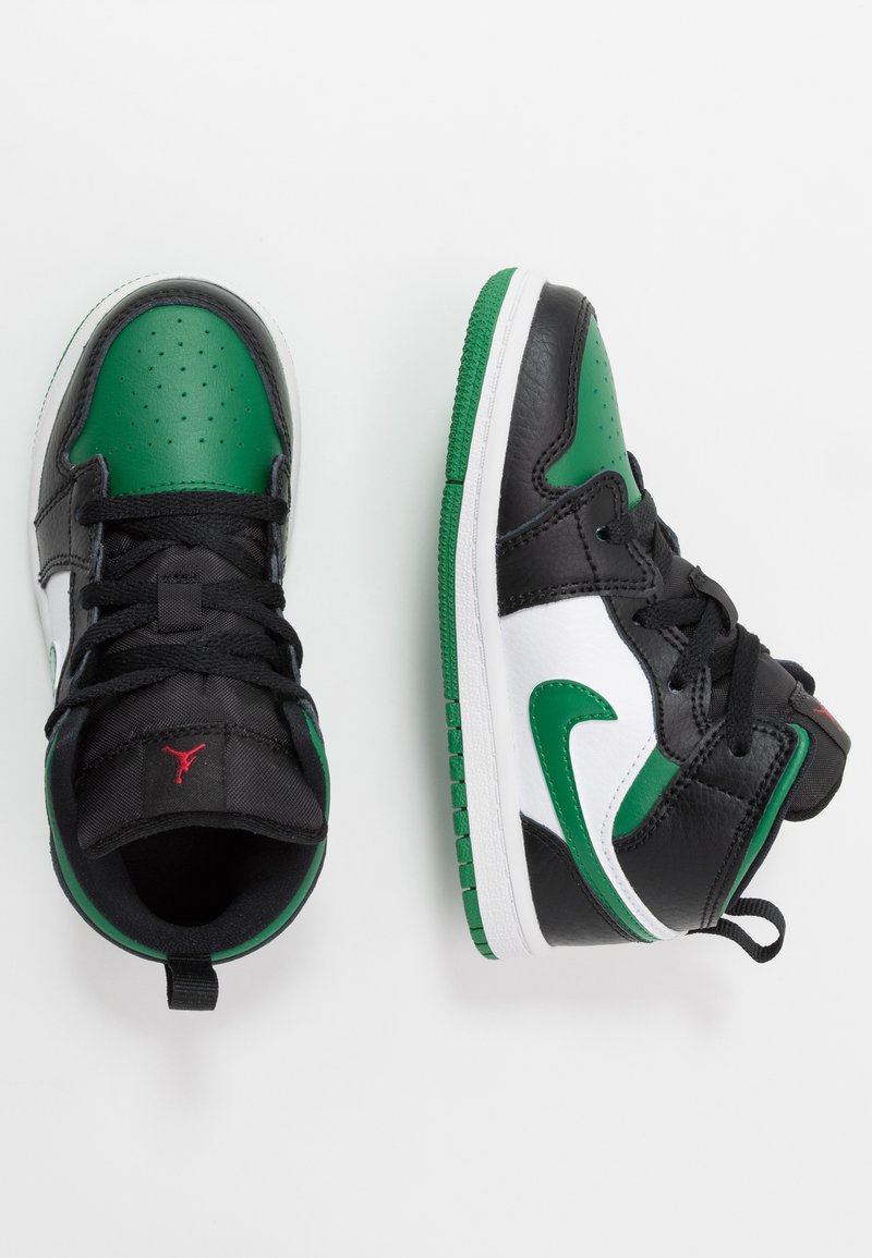 Paire de baskets montantes noires, vertes et blanches avec des lacets noirs, un swoosh Nike vert et un logo Jumpman rouge sur la languette noire.