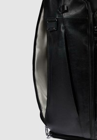 Mochila de cuero negro con textura suave, que cuenta con un compartimento principal con cremallera, bolsillo exterior y un forro de color claro.