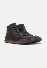Scarpe alte in pelle marrone con lacci blu scuro, suole in gomma e punte rotonde, con dettagli di cucitura minimi.