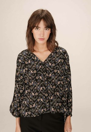 Blouse noire avec un motif floral en rose, bleu et jaune. Dotée d'un décolleté en V et de manches bouffantes trois-quarts. Texture de tissu douce.