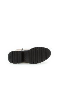 Semelle en caoutchouc noir avec des rainures texturées, comprenant un logo de marque. Design supérieur non visible, mettant l'accent sur la structure et le matériau de la semelle.