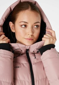 Padded jacket w kolorze jasnoróżowym z czarną podszewką. Posiada zamek błyskawiczny, kaptur ze sznurkiem oraz ściągacze z dzianiny. Logo umieszczone na klatce piersiowej.