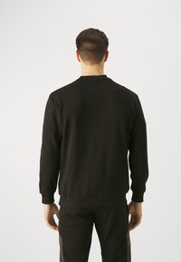 Czarny sweter wykonany z miękkiego materiału, z długimi rękawami, okrągłym dekoltem oraz ściągaczami przy rękawach i u dołu. Gładka faktura, prosty design.