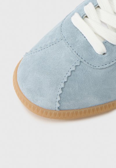 Γαλάζιο σουέντ παπούτσι με λευκά κορδόνια, με περίτεχνο ράψιμο και υφασμένο καουτσούκ σόλα με ζιγκ-ζαγκ μοτίβο κατά μήκος της άκρης.