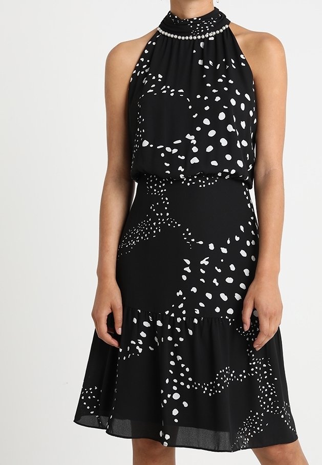 Robe noire sans manches avec des points abstraits blancs, col montant orné de perles semblables à des perles et jupe évasée.