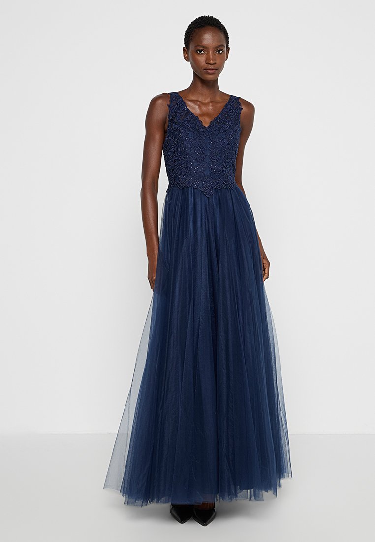 Granatowa suknia wieczorowa z dopasowanym, koronkowym gorsetem i zwiewną spódnicą z tiulu. Posiada dekolt w kształcie litery V i bezrękawowy fason.